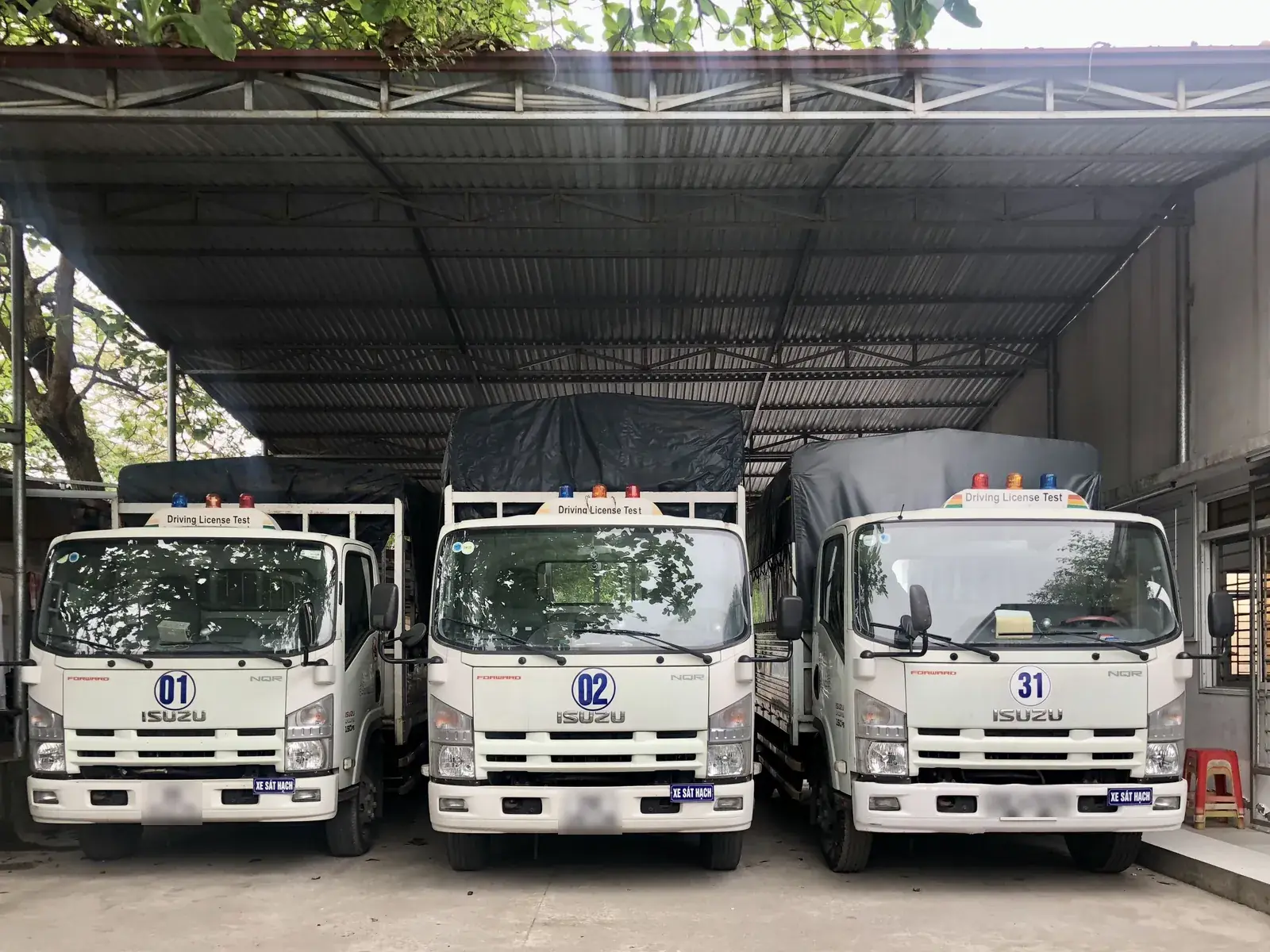 Ba xe tải sát hạch hạng C1 đỗ trong nhà xe